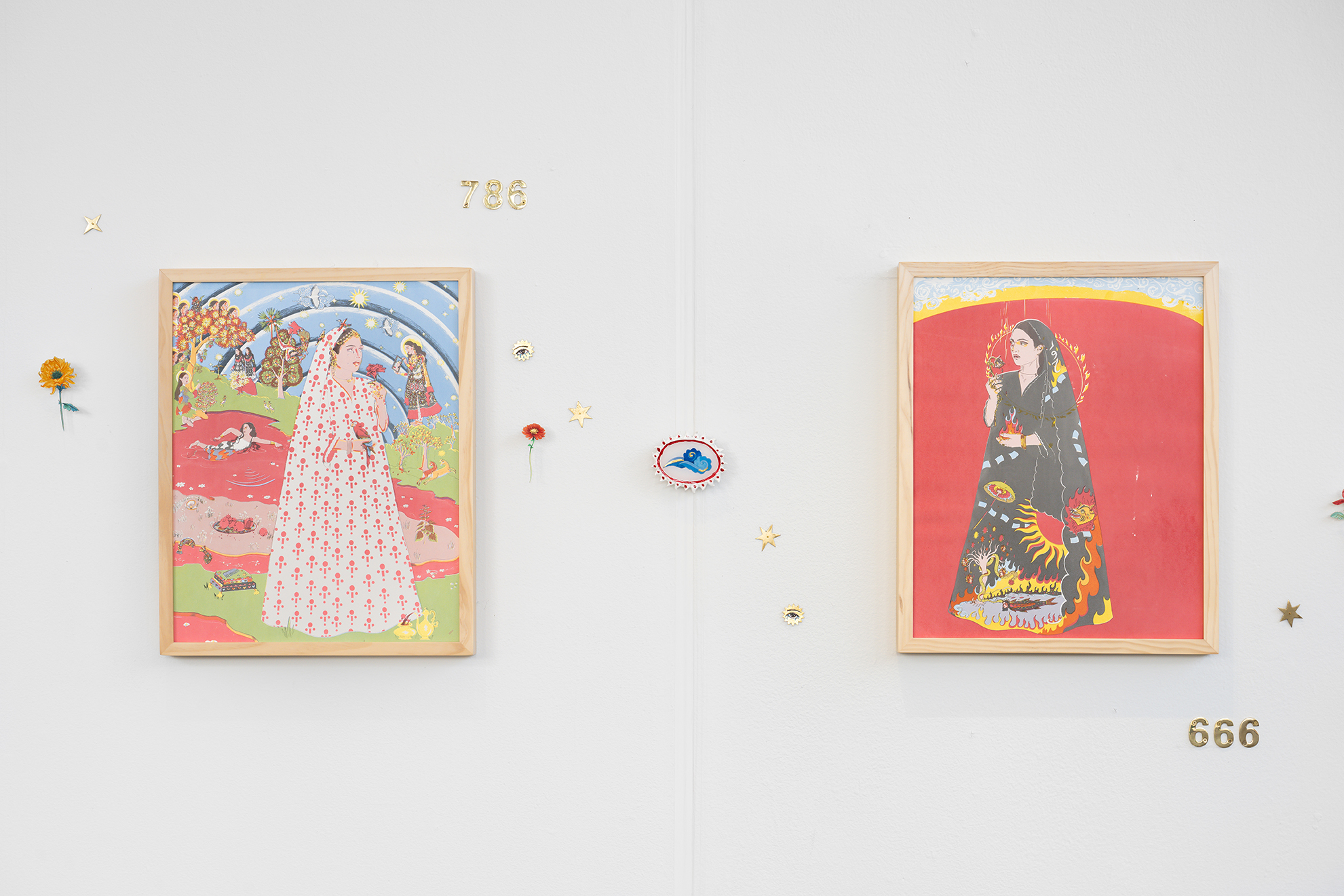Two framed figurative artworks hang on a white gallery wall decorated with small flowers, stars, and symbolic numbers. The left artwork portrays a woman in a white patterned dress within a vibrant landscape of pink water, trees, and celestial imagery. The right artwork shows a woman in a dark robe with fiery motifs against a bright red background. The numbers "786" and "666" appear above and below the works, respectively.