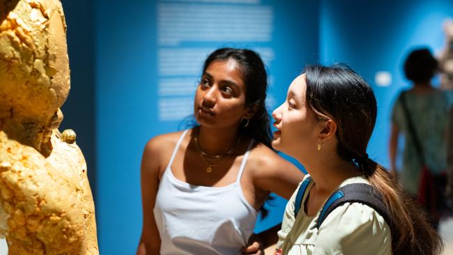 Two UMD students looking at a "Mother Mold" sculpture by artist Coralina Rodriguez Meyer.